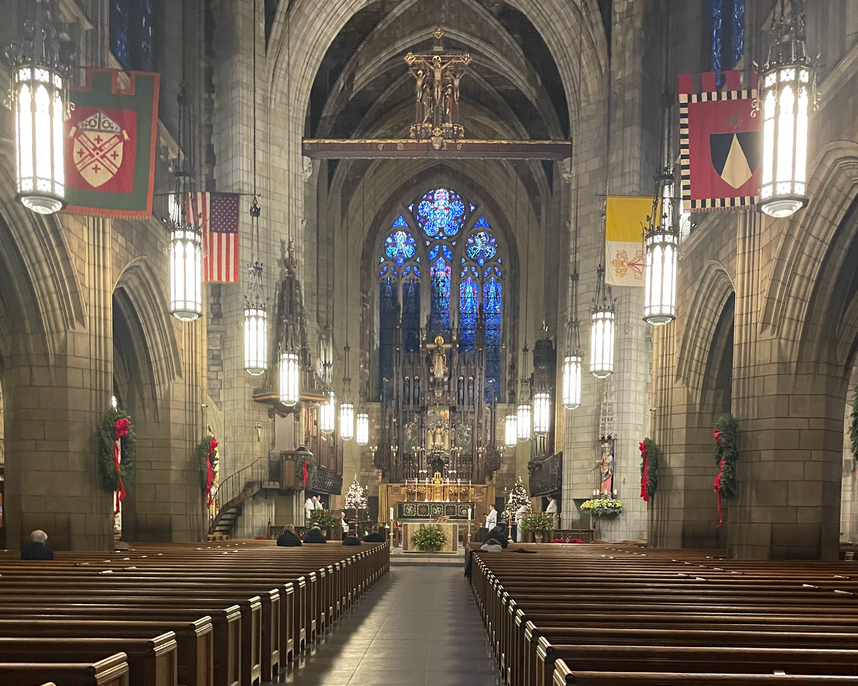 Narrow view of a church nave with pews and stained glass window